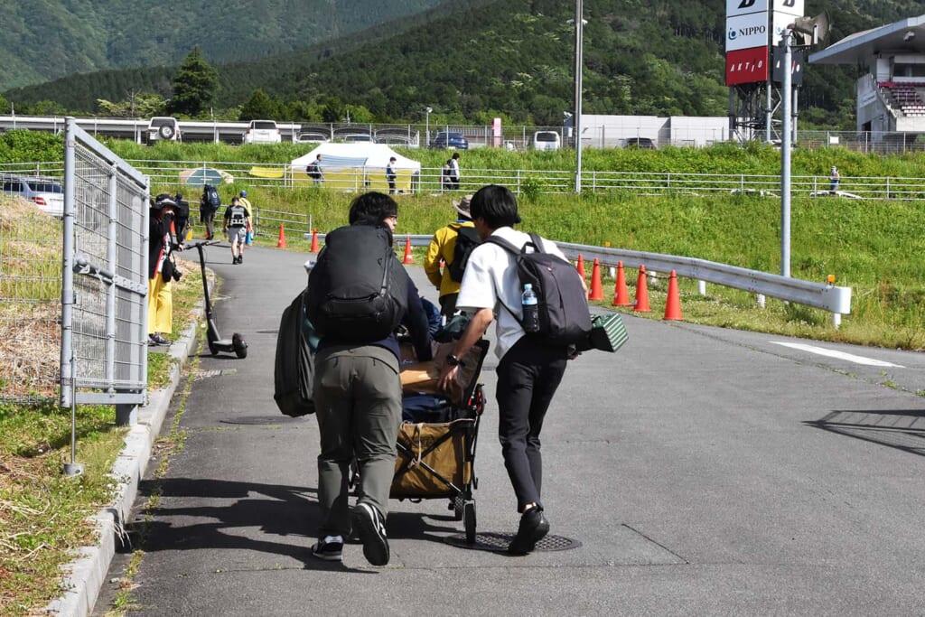 アウトドアワゴンでキャンプ道具を運ぶ観戦者