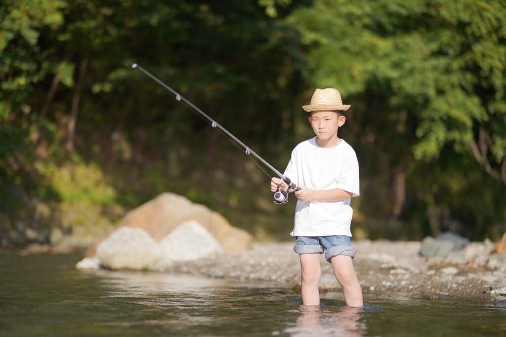 渓流で釣りをする少年