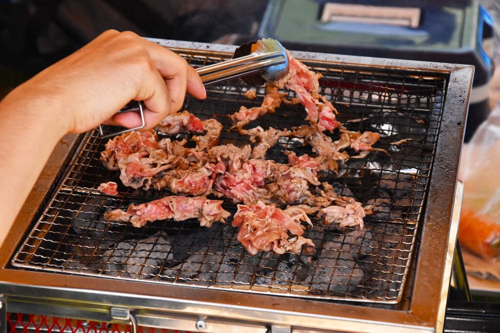 BBQグリルで肉を焼くキャンパー