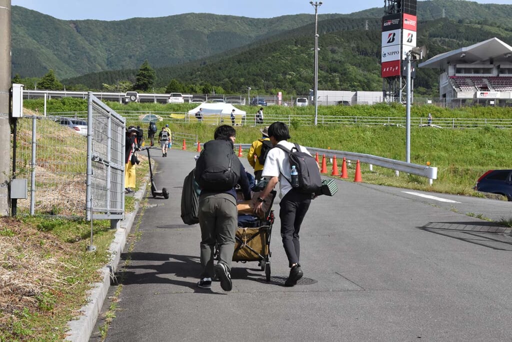 アウトドアワゴンでキャンプ道具を運ぶ観戦者