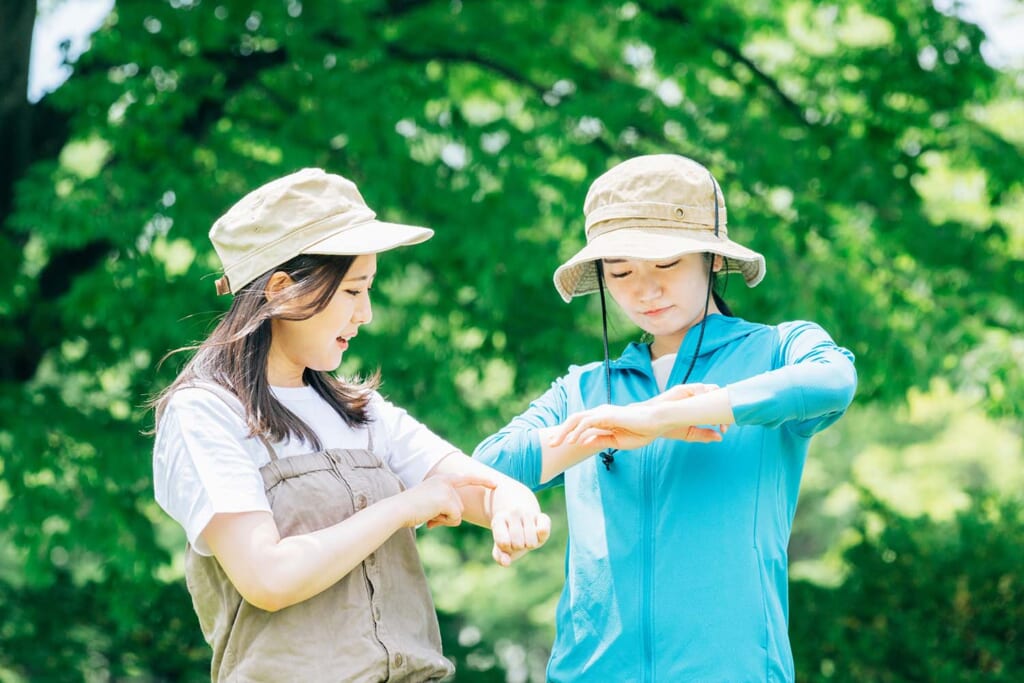 虫刺されで腕を気にする女性