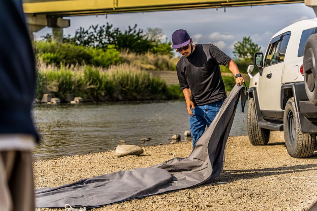 河原でテントを設営する男性