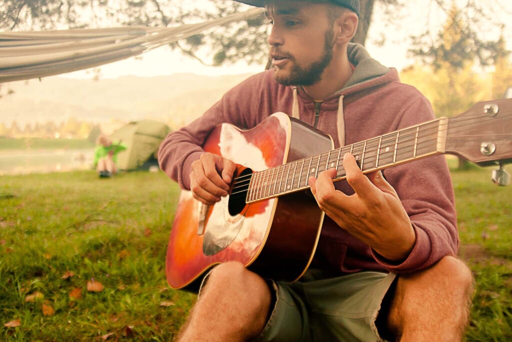 キャンプでギターを弾く男性