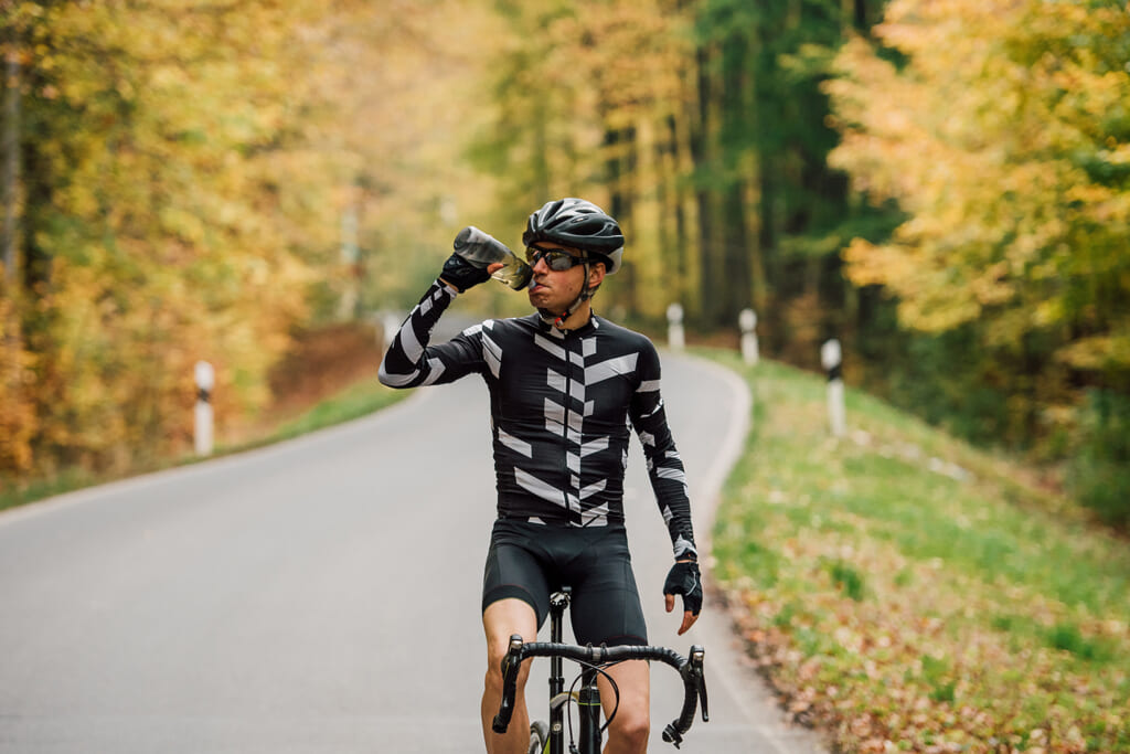 自転車に乗りながら水を飲む男性