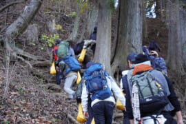 勾配のある山中を登る参加者の後ろ姿