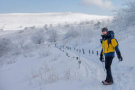 装備を固めて雪山を歩く男性