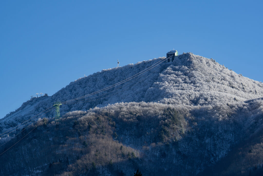 うっすらと雪に覆われた山とロープウェイ