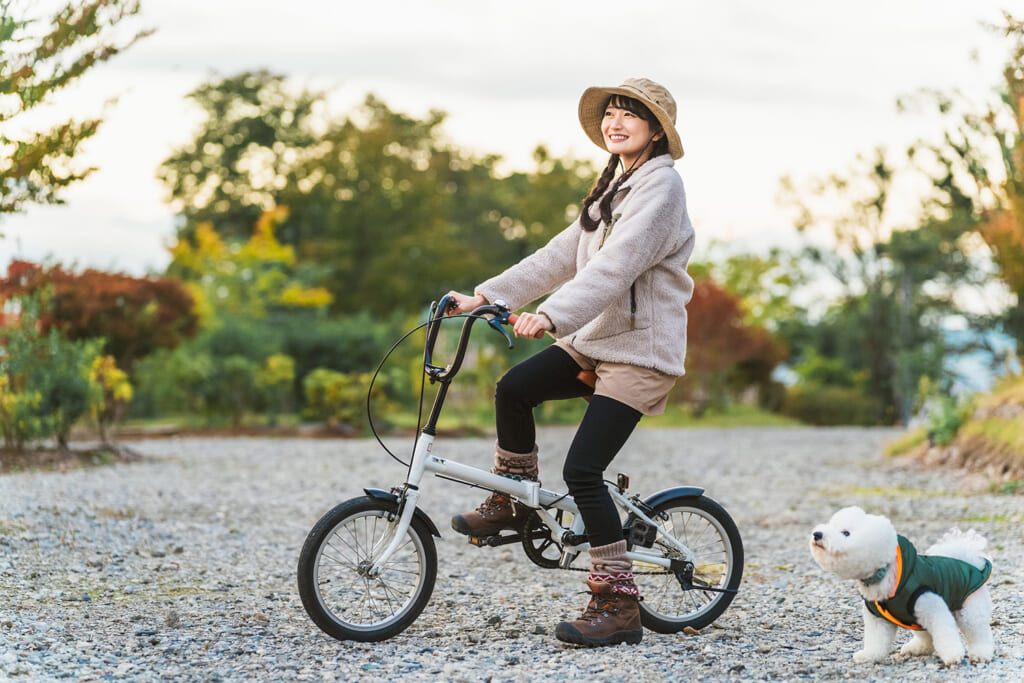 犬を連れてサイクリングする女性キャンパー