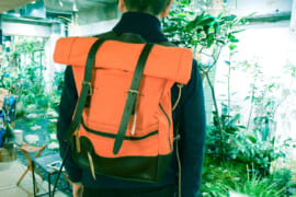 オレンジ色のバックパックを背負っている人
