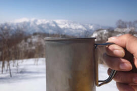 冬山でカップを掲げている